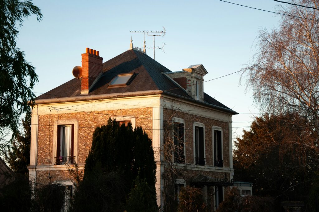 Maison en béton brun et blanc près des arbres pendant le coucher du soleil